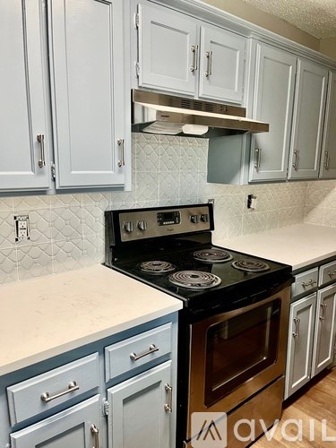 A kitchen with a black stove top oven and blue cabinets.