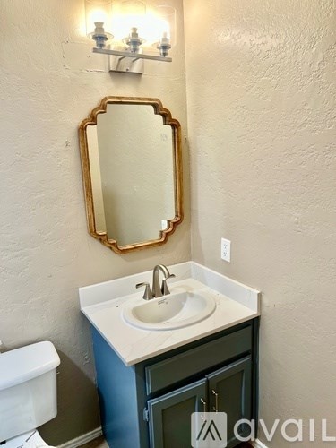A bathroom with a sink, mirror, and light fixture.
