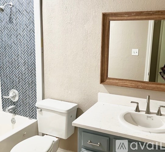 A bathroom with a toilet, sink, and mirror.
