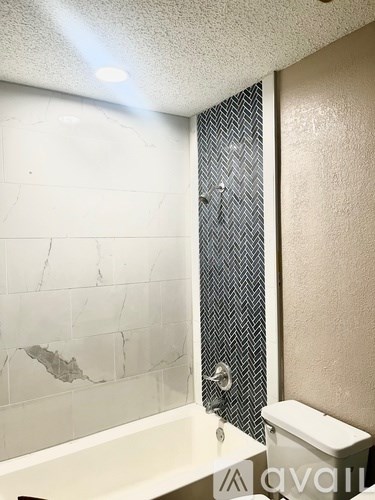 A bathroom with a marble tile wall and a shower with a glass door.
