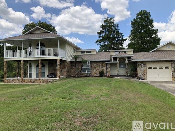 A house with a stone wall and a carport is for sale.