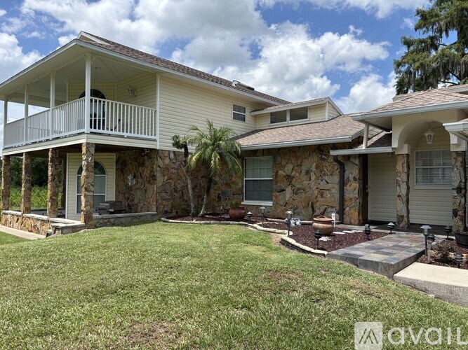 A house with a stone wall and a white porch.