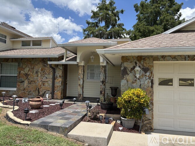 A house with a white garage door and a stone wall.