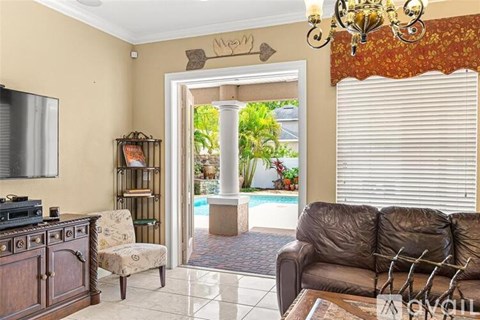 A living room with a brown leather couch and a chandelier.