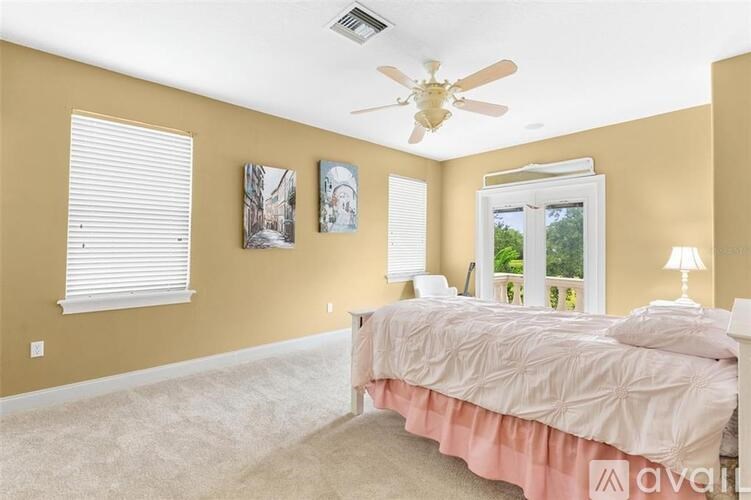 A bedroom with a bed, a ceiling fan, and two pictures on the wall.