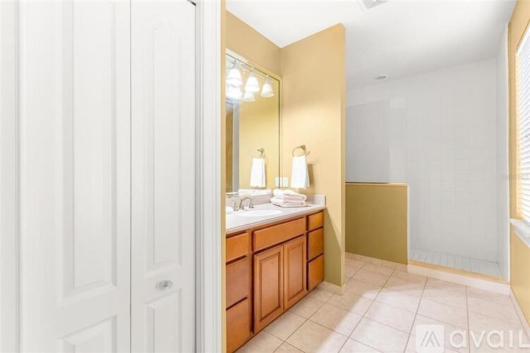A bathroom with a white door and a brown vanity.