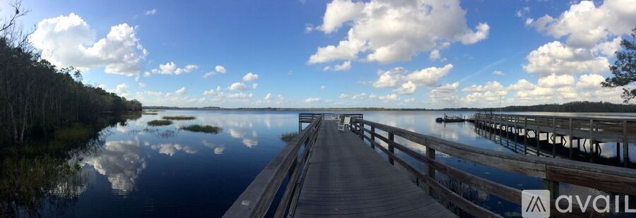 A wooden dock extends into a calm body of water with a cloudy sky above.