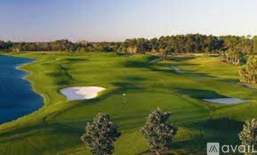 A golf course with a lake and trees in the background.