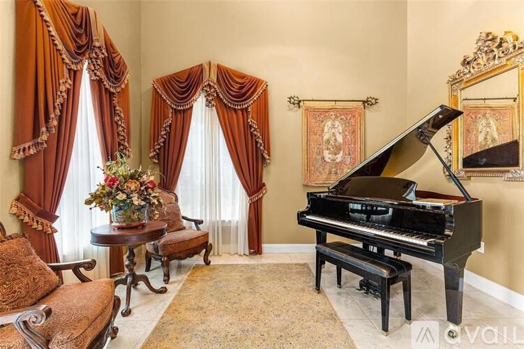 A grand piano sits in a room with a table and chairs.