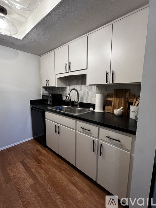 A kitchen with white cabinets and a black countertop.