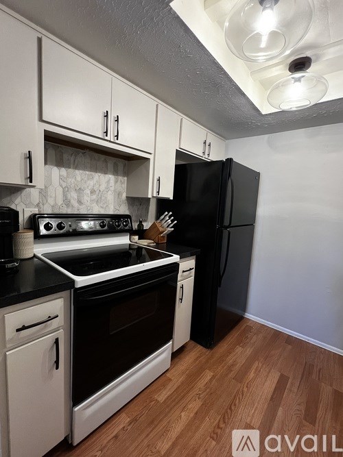 A kitchen with black and white appliances and wooden floors.