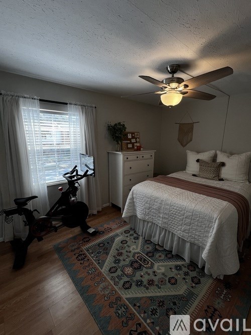 A bedroom with a bed, dresser, and exercise bike.