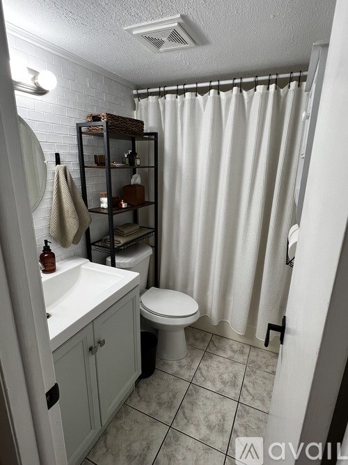 A bathroom with a white toilet, sink, and shower curtain.