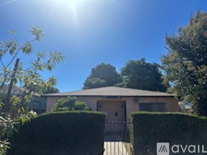 A house with a fence and hedges in front of it is for sale.