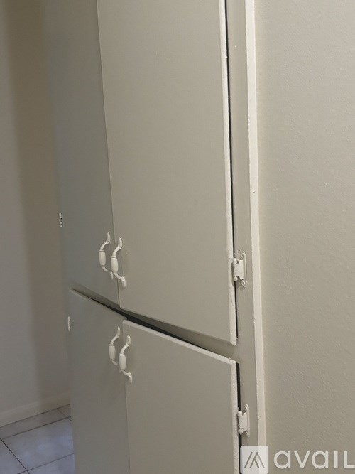 A white cabinet with a black handle is mounted on a white wall.