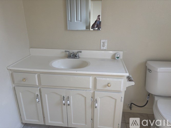 A white bathroom vanity with a sink and a mirror above it.