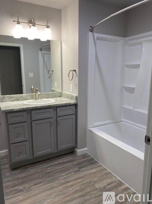 A bathroom with a sink, mirror, and bathtub.