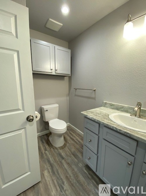 A bathroom with a toilet, sink, and cabinets.