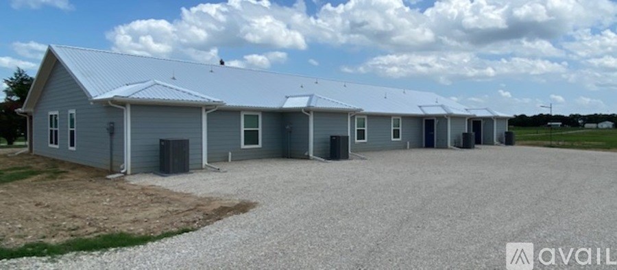 A row of identical buildings are lined up in a field.