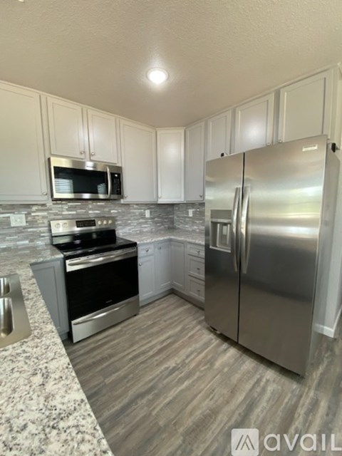 A kitchen with a stainless steel refrigerator and microwave above the oven.