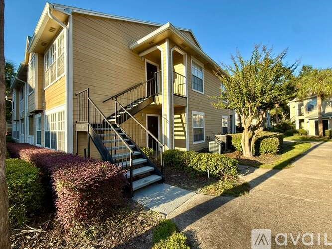 A beige two-story apartment building with a balcony on the second floor.