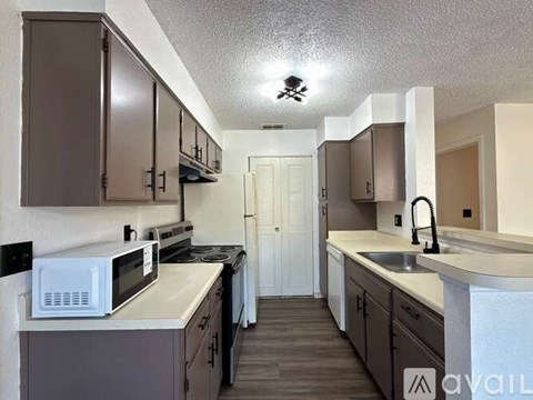 A kitchen with brown cabinets and a white microwave.