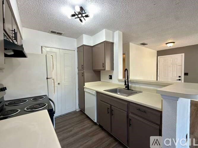 A kitchen with a stove top oven, sink, and cabinets.