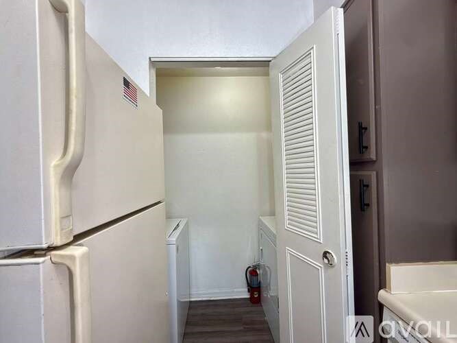 A white refrigerator is in a kitchen with a white door.