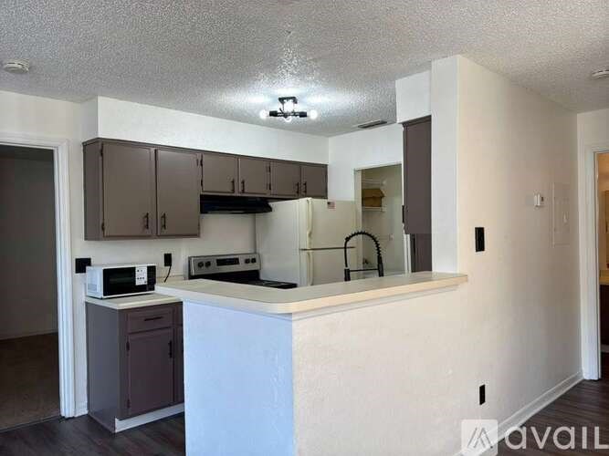 A kitchen with a white counter and brown cabinets.