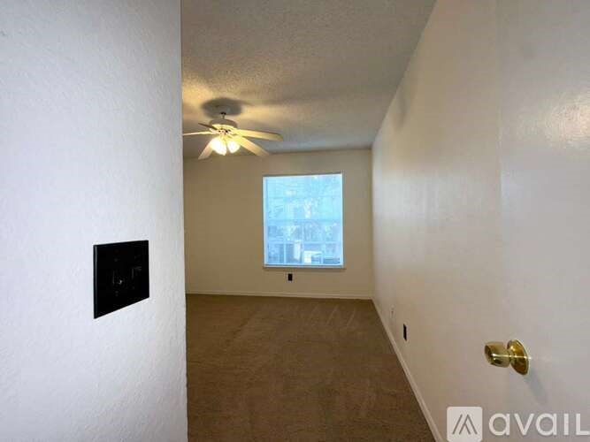 A room with a ceiling fan and a window overlooking a cityscape.