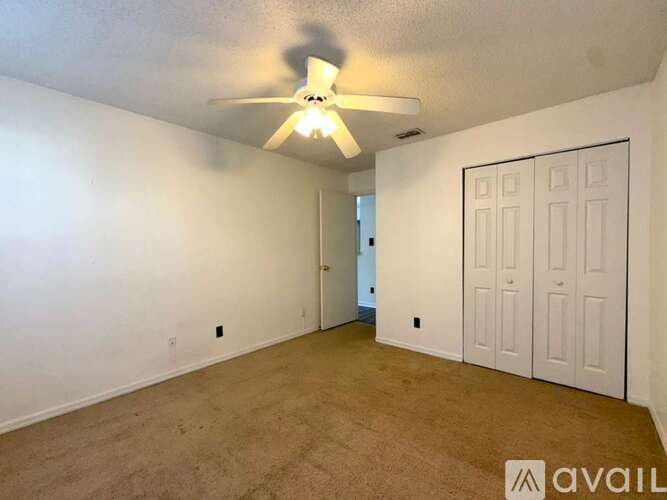 A room with a ceiling fan and two doors.
