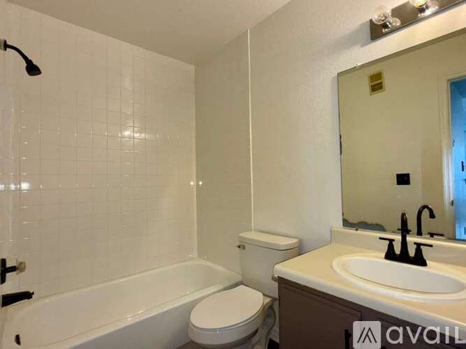A white tiled bathroom with a toilet, sink, and bathtub.