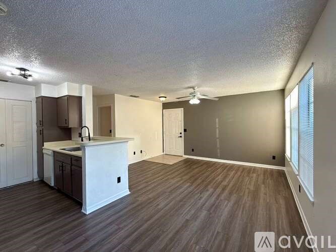 A spacious room with a kitchen area and wooden flooring.