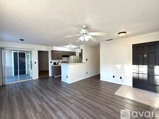 A spacious living room with wood flooring and a ceiling fan.