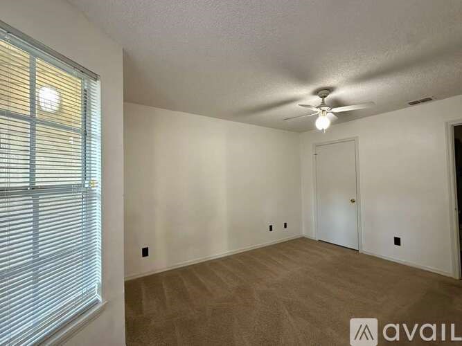A room with a ceiling fan and a window with blinds.