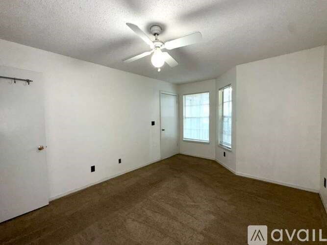 A room with a ceiling fan and carpeted floor.