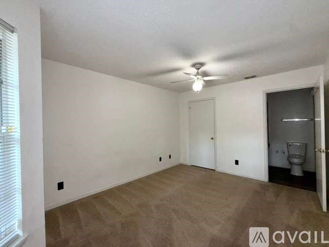 A room with a ceiling fan and a toilet in the corner.