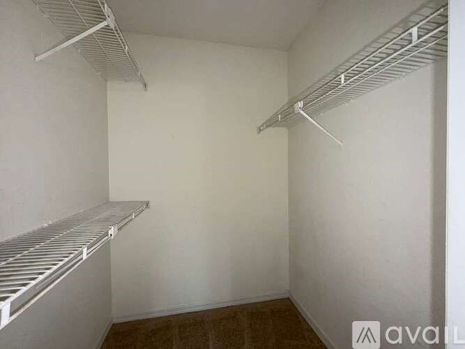 A white wall with two metal shelves.