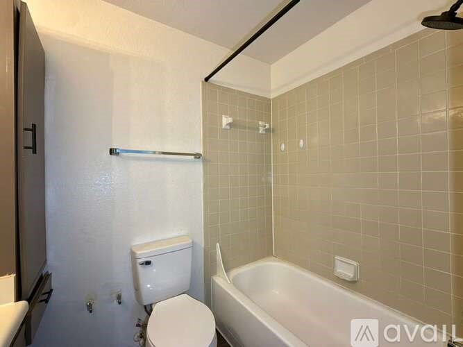 A white toilet sits next to a bathtub in a bathroom with white tiles.