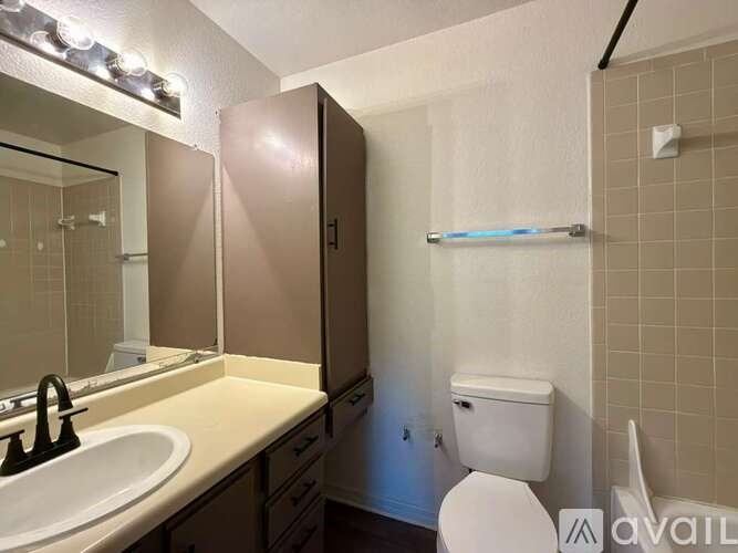 A bathroom with a toilet, sink, and mirror.
