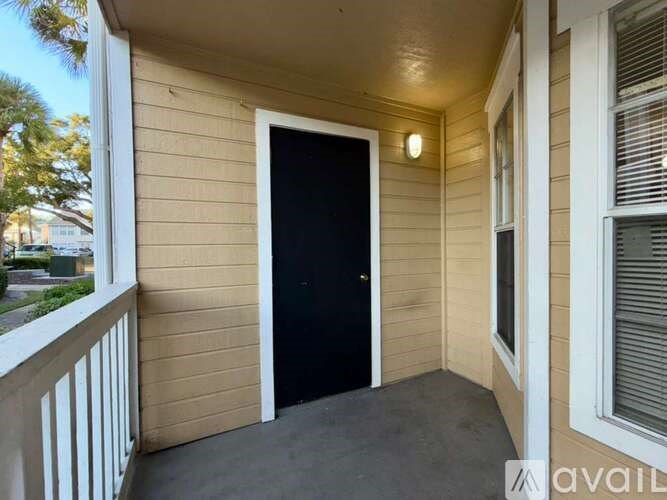 A balcony with a black door and a window with blinds.