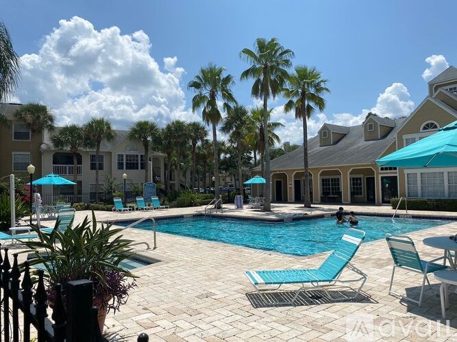 A pool surrounded by palm trees and blue umbrellas.