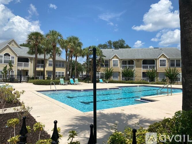 A pool surrounded by palm trees and a building in the background.