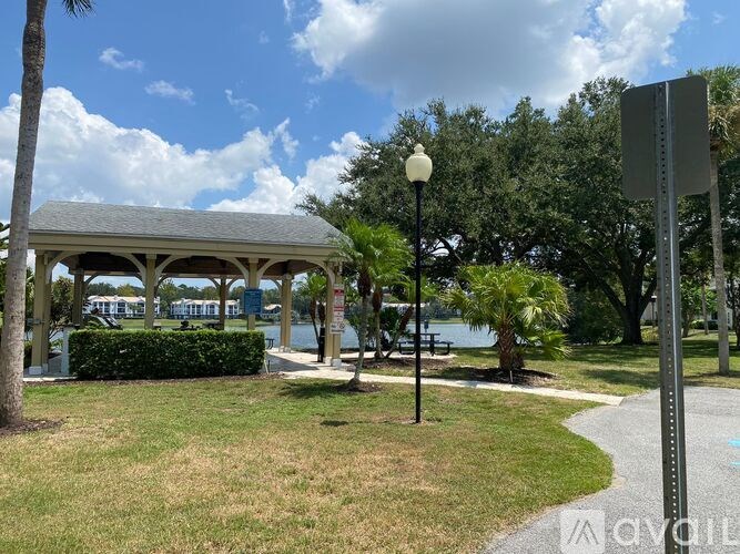 A gazebo is situated in a park with a body of water in the background.