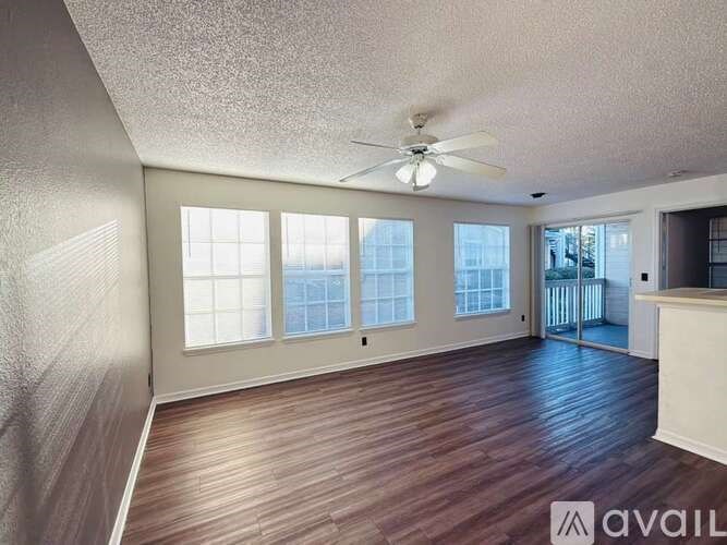 A room with a ceiling fan and sliding glass doors.