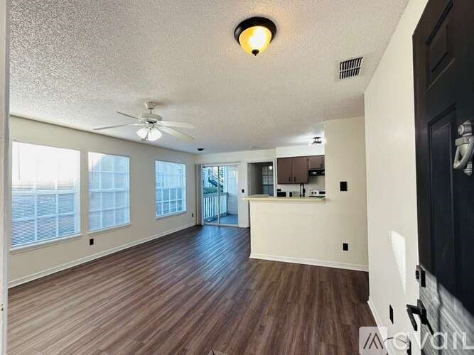 A spacious room with wood flooring and a ceiling fan.
