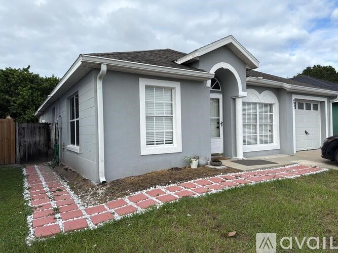 A house with a grey exterior and a brick pathway leading to the front door.