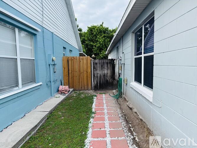 A narrow alley between two houses with a wooden fence and a brick pathway.