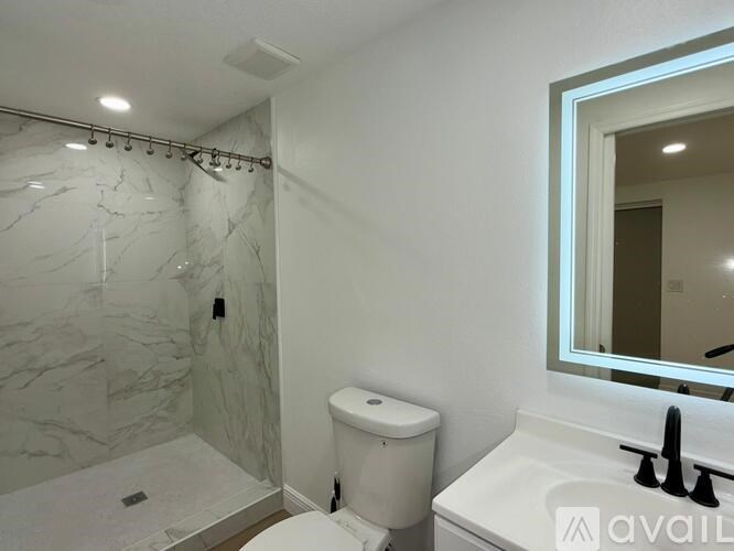 A bathroom with a marble shower, toilet, and sink.