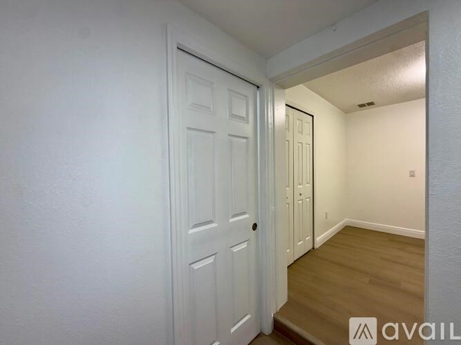 A white door is in a room with wooden floors and white walls.